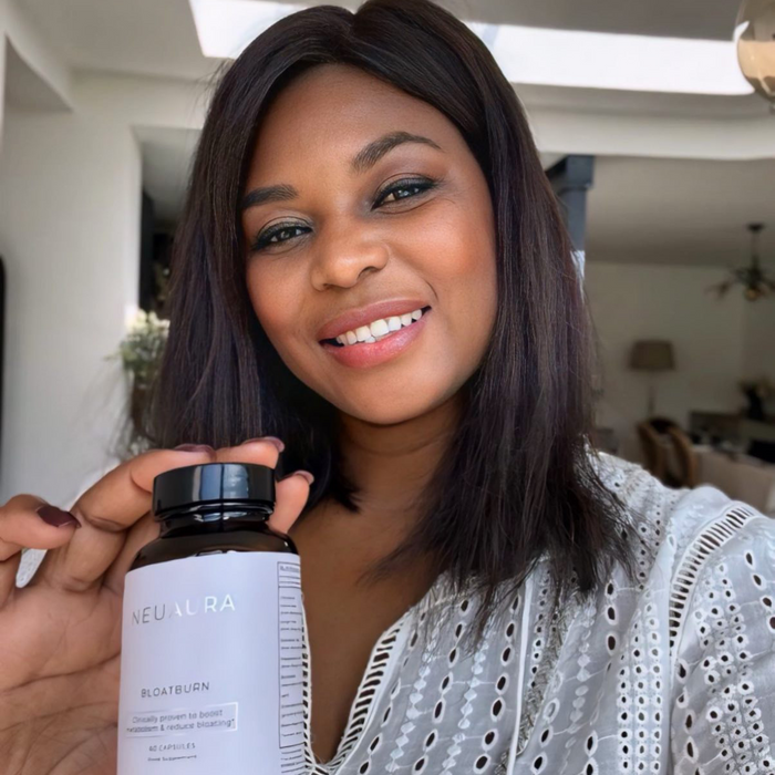 A person smiling and holding a bottle labeled 'Metabolic+' in a bright, well-lit room.