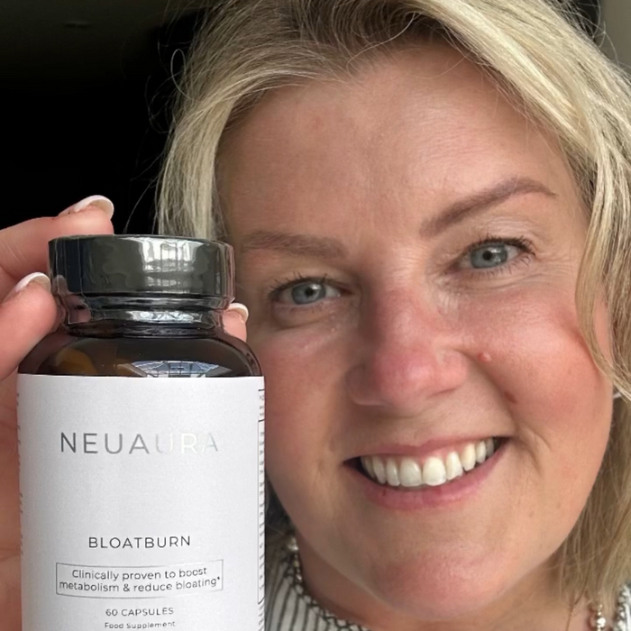 A person smiling and holding a bottle labeled 'Metabolic+' in a bright, well-lit room.