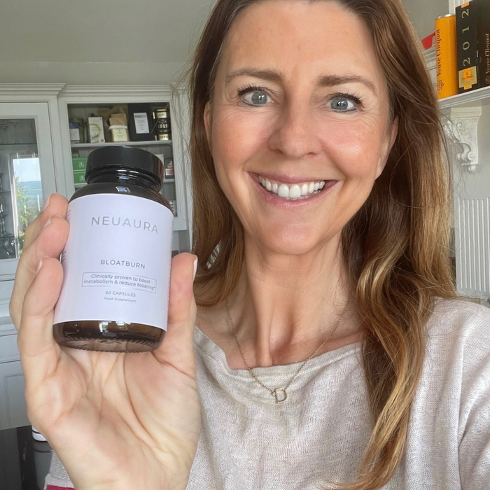 A person smiling and holding a bottle labeled 'Metabolic+' in a bright, well-lit room.